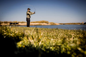 Entspannter TROUT FISHER am Wasser im Moment des Auswurfs mit aufgeladener Angelrute